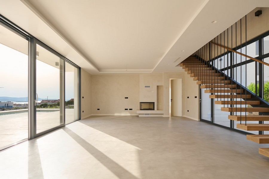 Světlý obývací pokoj vily v Chorvatsku s krbem a velkými okny, na prodej