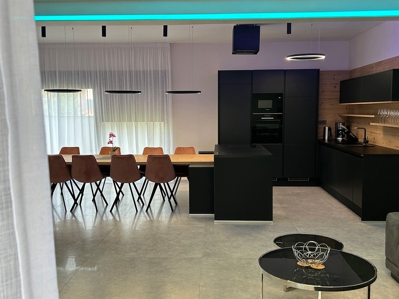 Otevřená kuchyně a jídelní kout s výhledem na kulečníkový stůl a obývací prostor