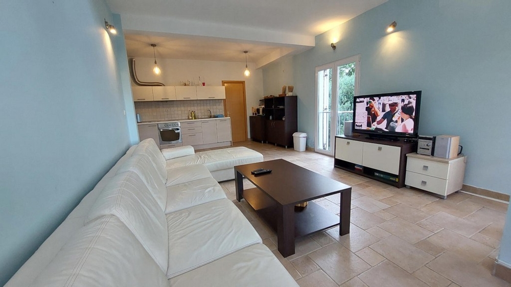 Obývací prostor s bílou pohovkou, konferenčním stolkem a TV v domě v Chorvatsku