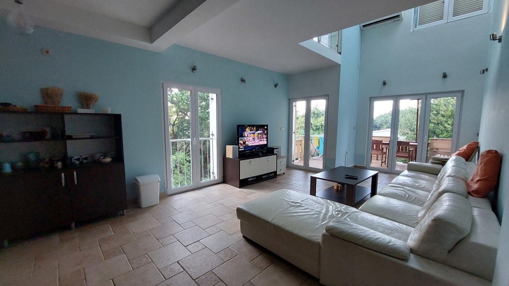 Prostorný obývací pokoj s bílou pohovkou, TV a jídelním koutem v domě v Chorvatsku