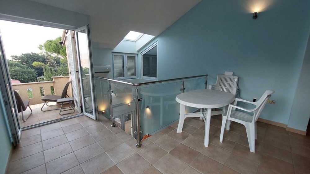 Galerie se stolem a židlemi vedoucí na balkon v domě v Chorvatsku