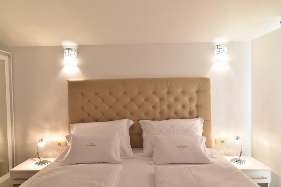 Detail postele v ložnici s moderním osvětlením v nabídce realitní kanceláře Panorama Scouting