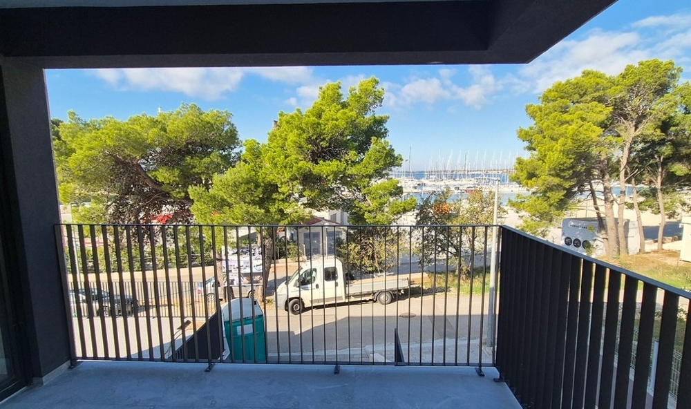 Terasa moderní vily s bazénem, ​​lehátky a venkovním posezením obklopená bujnou zelení v Drage, Chorvatsko.