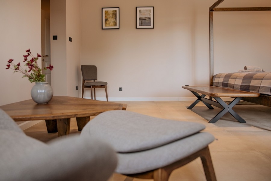 Moderní a elegantní ložnice s psacím stolem, nástěnnou TV a velkým zrcadlem, s jemným osvětlením a neutrálními tóny