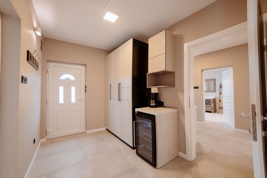 Vstupní prostor s moderními skříněmi, vinotékou a průhledem do stylové koupelny