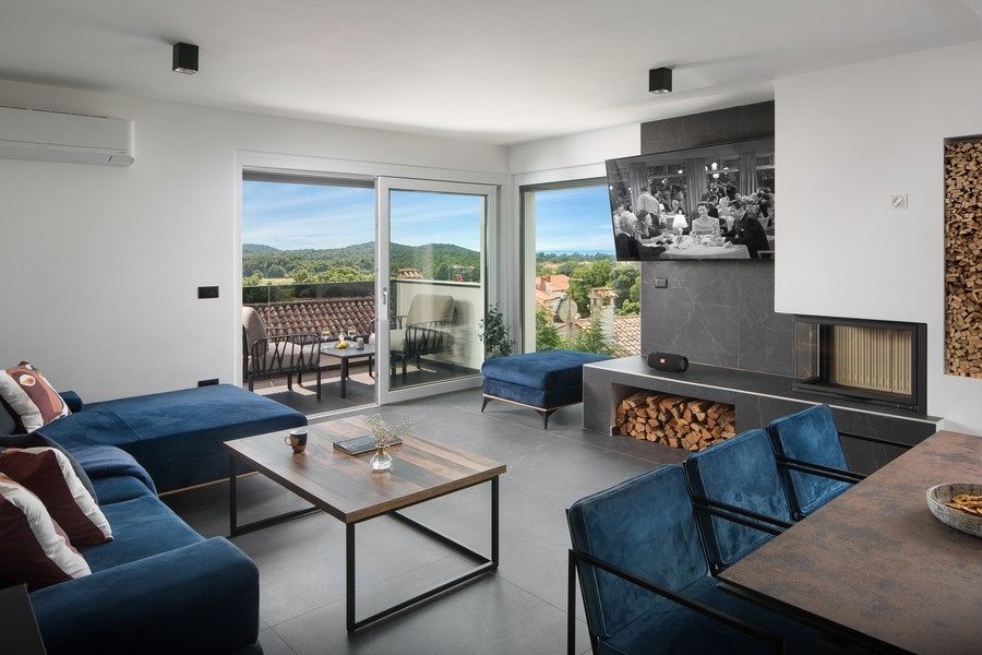 Moderní obývací pokoj s vysoce kvalitním krbem a výhledem na moře.