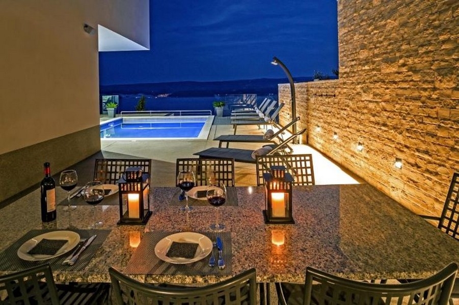 Jídelní stůl a výhled na bazén ve večerní atmosféře.