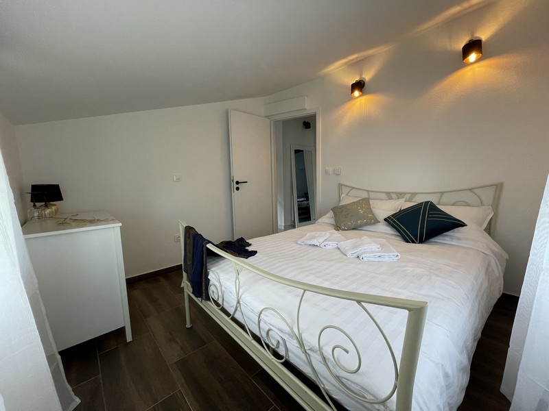 Ložnice s bílou kovanou postelí, dekorativními polštáři a moderním prostředím