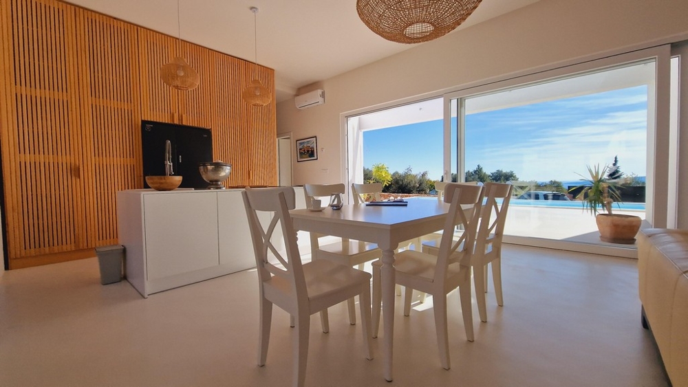 Otevřený obývací a jídelní kout s výhledem na terasu a bazén vily na Krku v Chorvatsku.