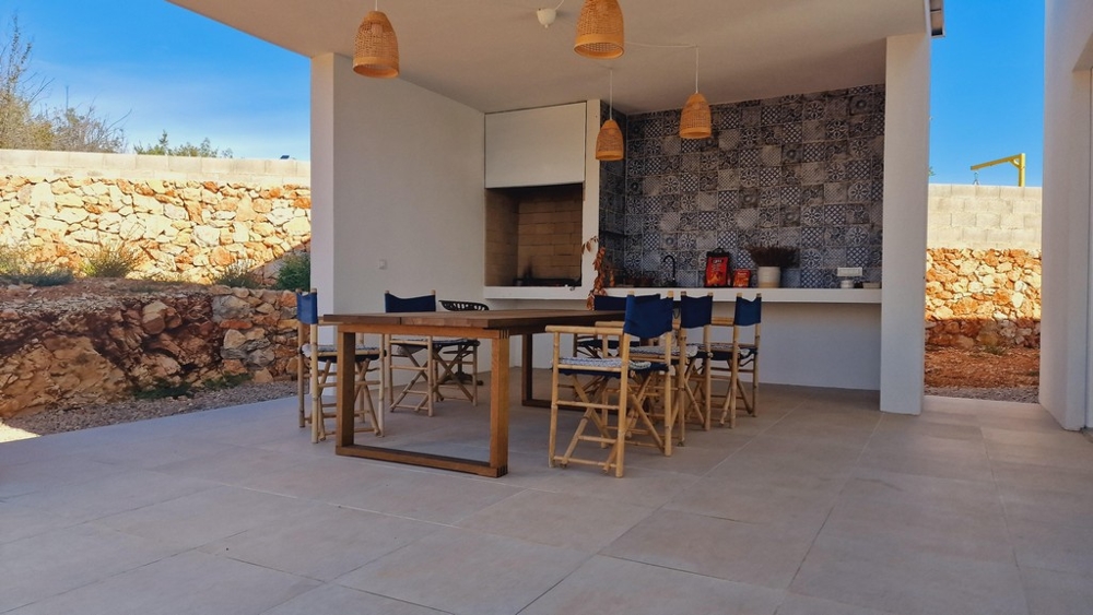 Krytá venkovní letní kuchyně s jídelním stolem a židlemi