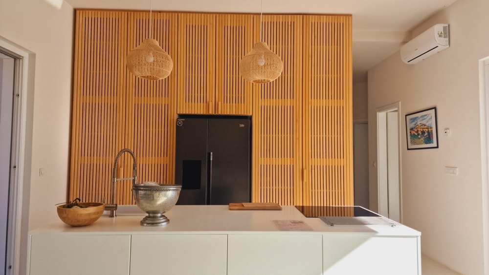 Moderní kuchyňská linka s dřevěným obložením a ostrůvkem, vybavená spotřebiči