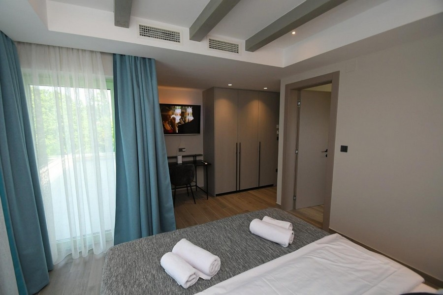 Ložnice s velkými okny, modrými závěsy a moderním interiérem