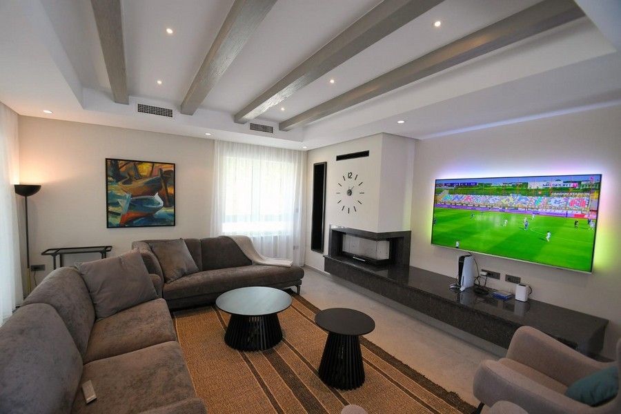 Moderní obývací prostor s velkou TV a krbem.