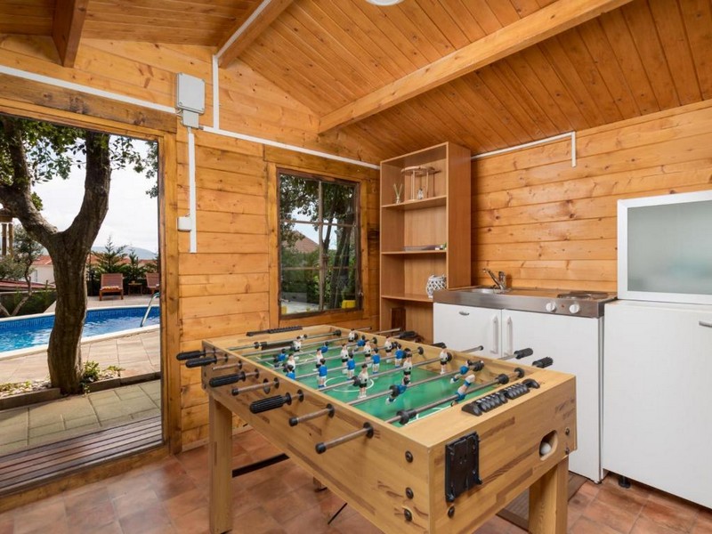 Zahradní domek se stolním fotbalem a výhledem na bazén.
