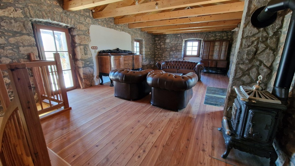 Velký obývací pokoj v patře s koženými křesly a kamny na dřevo.
