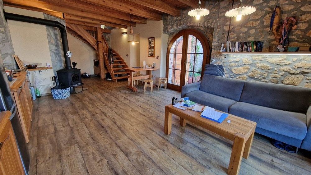 Otevřený obývací pokoj s odhalenými trámy, kamny na dřevo a rustikálním interiérem.