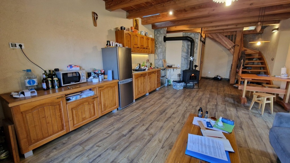 Kuchyně s dřevěnými skříňkami, lednicí a jídelním stolem v rustikálním stylu.