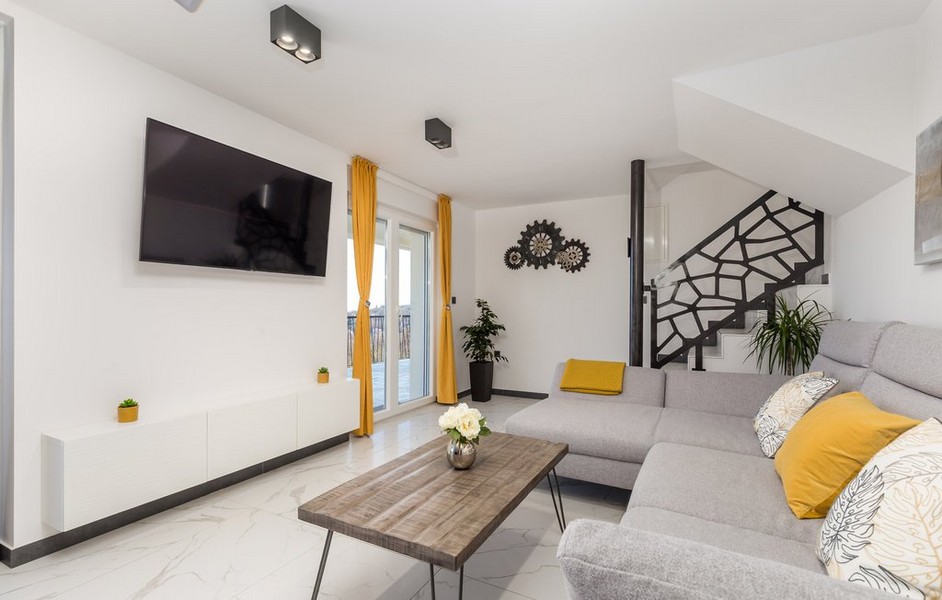 Moderní obývací pokoj s šedou pohovkou a žlutými akcenty