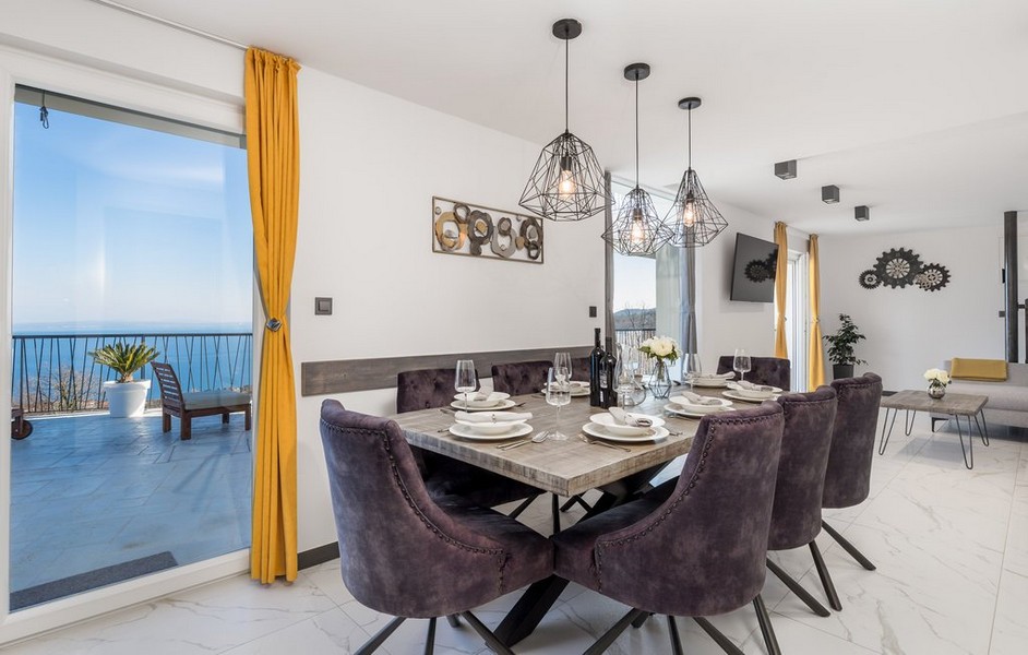 Jídelní kout s moderními židlemi a závěsnými svítidly