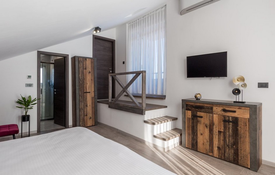 Ložnice s rustikálním dřevěným nábytkem a schodištěm