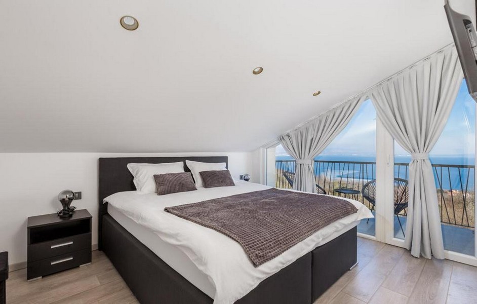 Ložnice se zkoseným stropem a výhledem na moře