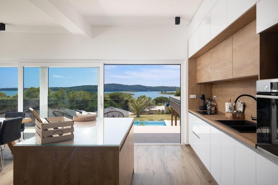 Moderní kuchyně s výhledem na bazén a moře.
