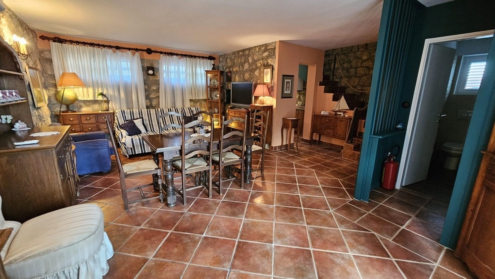 Útulný obývací pokoj s jídelním koutem, kamennou zdí a dřevěným nábytkem