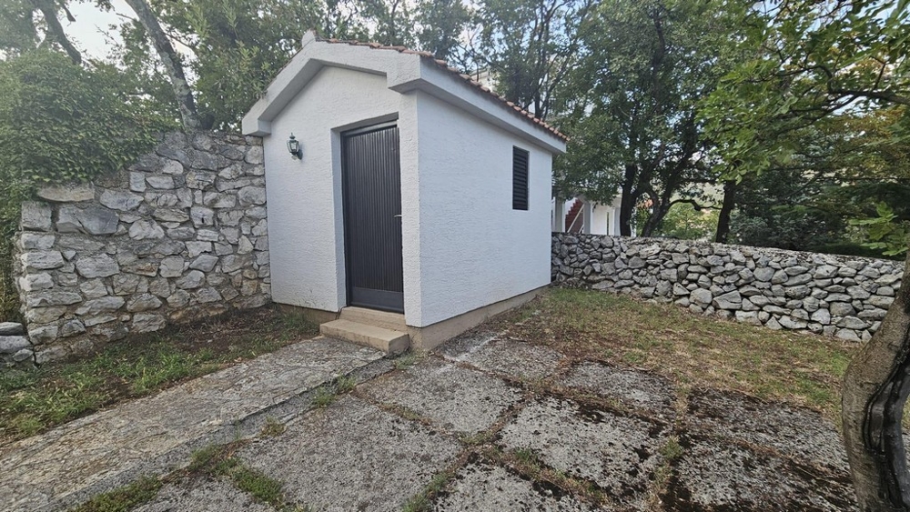 Malá přístavba v zahradě s kamennou zdí