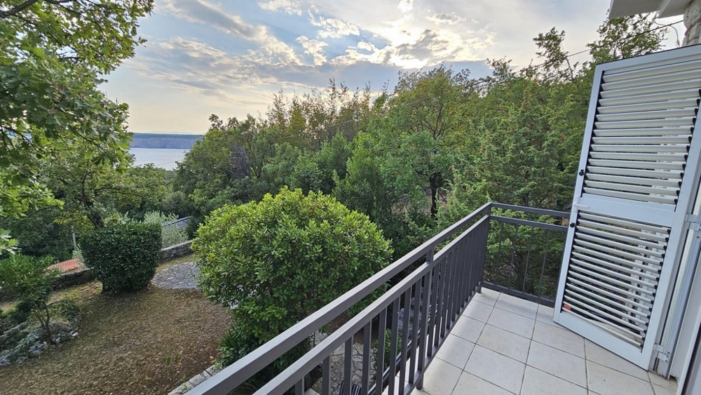 Balkon s výhledem na stromy a moře v pozadí