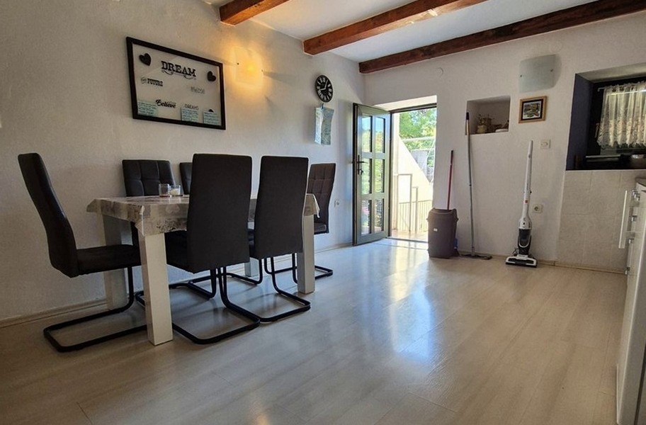 Světlá jídelna s moderním nábytkem a dřevěnými trámy.