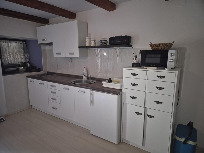 Moderní bílá kuchyně s malými skříňkami a policemi.