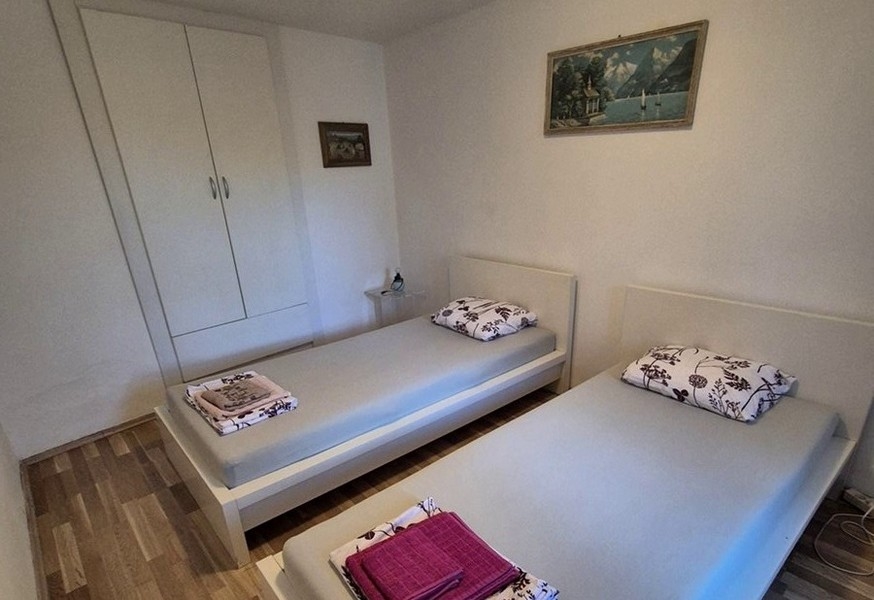 Ložnice se dvěma samostatnými lůžky a jednoduchým nábytkem.