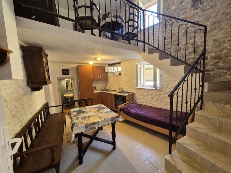 Obývací pokoj v rustikálním stylu s dřevěnými trámy a kamennými schody.