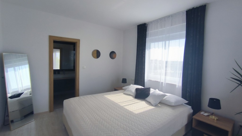 Druhá ložnice s velkou postelí a přilehlou koupelnou.