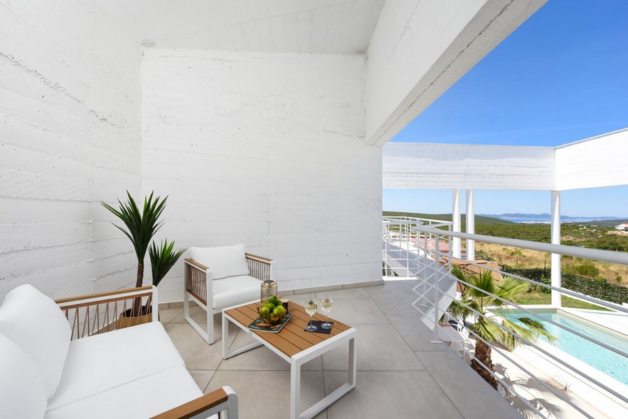 Krytá terasa s posezením a výhledem na bazén a okolí.