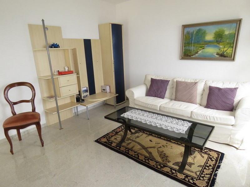 Útulný obývací pokoj s policí a dekorativním kobercem.