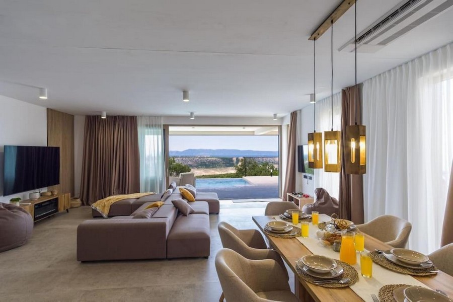 Moderní a luxusně zařízený obývací pokoj s jídelním koutem a výhledem na bazén.