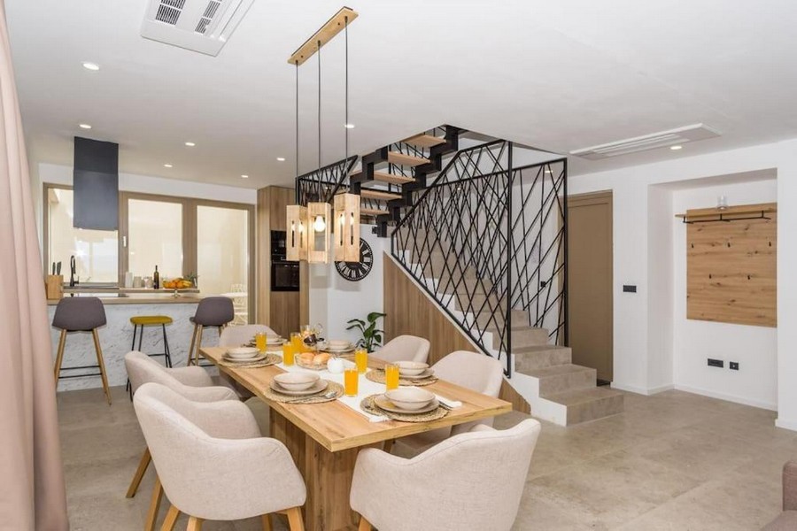 Pohled na jídelní stůl a kuchyň i na moderní schodiště vily.