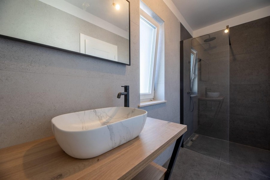 Koupelna a moderní umyvadlo v kamenném vzhledu.