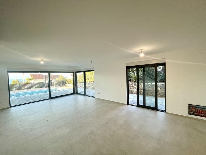 Světlý obývací prostor s proskleným průčelím a výhledem na bazén