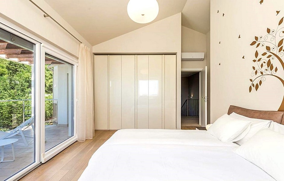 Světlá ložnice s balkonem a moderním nábytkem