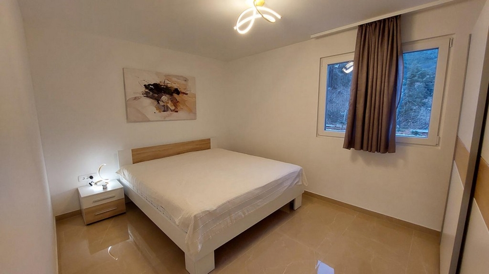 Ložnice s manželskou postelí a neutrálním nábytkem