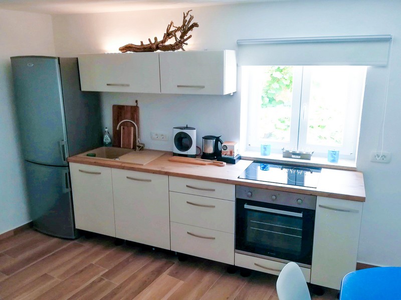 Světlá kuchyně s dřevěnými pracovními deskami a moderním vybavením