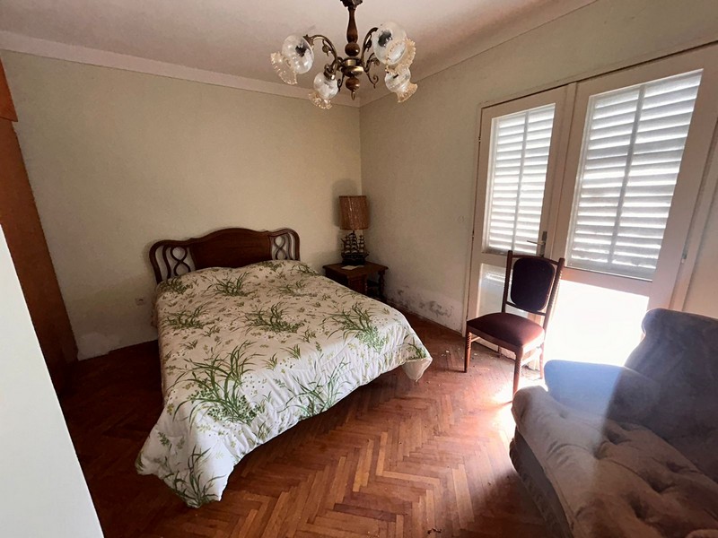 Ložnice s manželskou postelí, světlým oknem a starým nábytkem