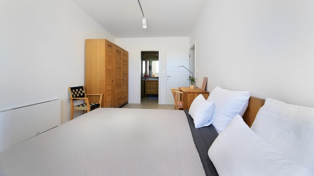 Pohled ze živého plotu na bazén a salonek se vstupem do vily.