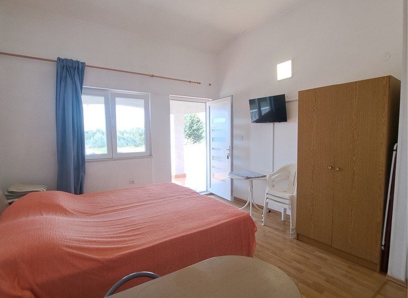 Ložnice s postelí, TV a dveřmi na venkovní terasu.