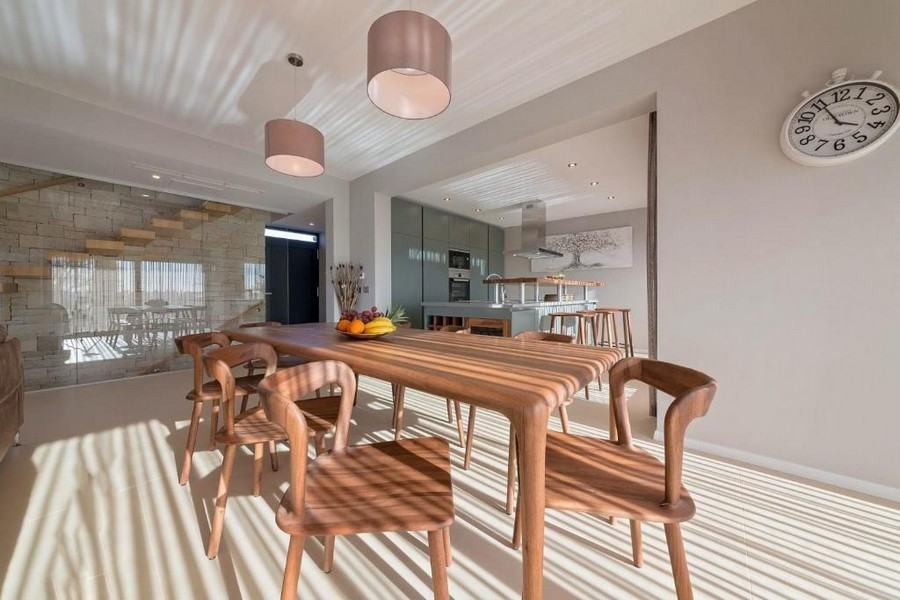 Jídelna s dřevěným stolem a přímým vstupem do kuchyně