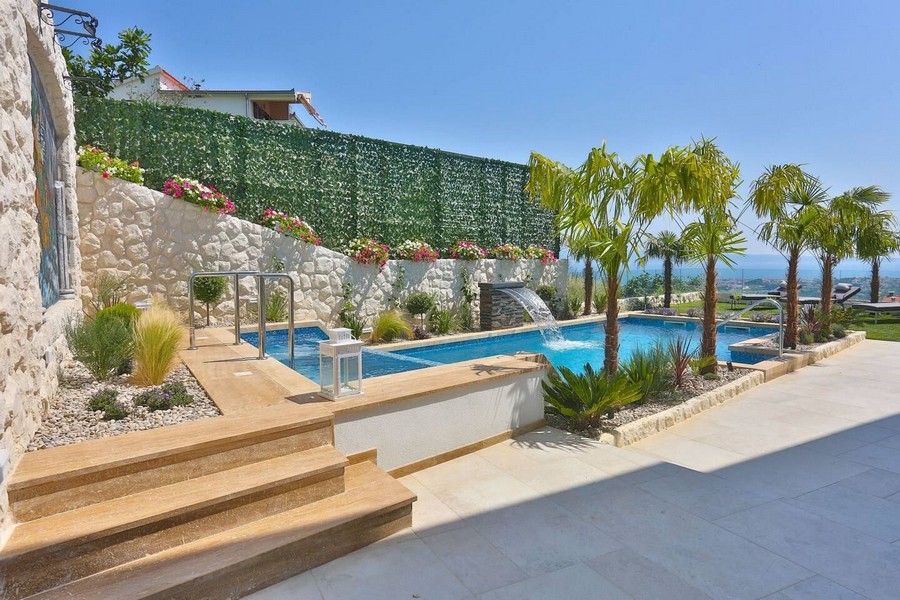 Moderní bazén s vodopádem a palmami