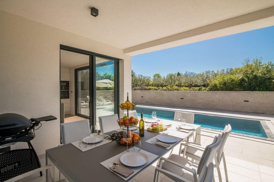 Krytá terasa s jídelním stolem a výhledem na bazén