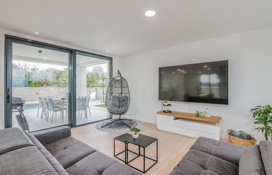 Moderní obývací pokoj s velkým proskleným průčelím a TV